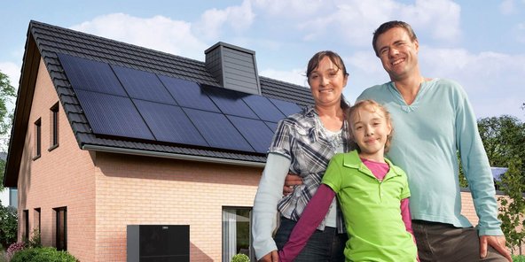 Eine kleine Familie, im Hintergrund ist ein Haus mit einer Photovoltaikanlage