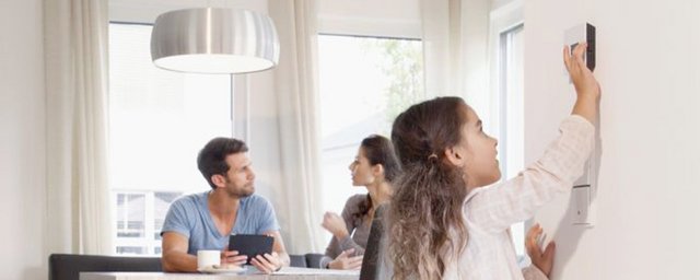 Ein Mann und eine Frau sitzten an einem Tisch, das Kind bedient einen Digitalregler